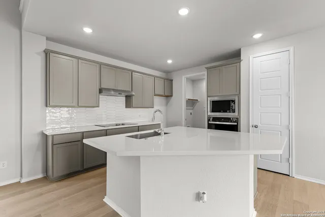 a kitchen with kitchen island a sink appliances and cabinets