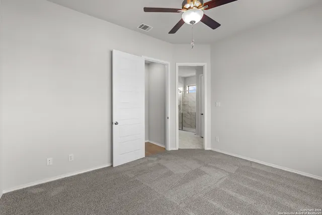 an empty room with chandelier fan and windows