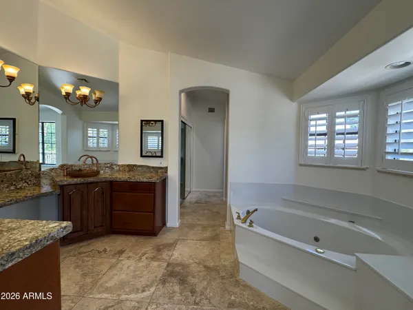 a spacious bathroom with a granite countertop tub double vanity and a mirror