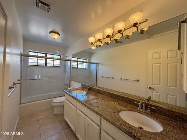 a bathroom with a granite countertop sink a toilet a mirror and shower
