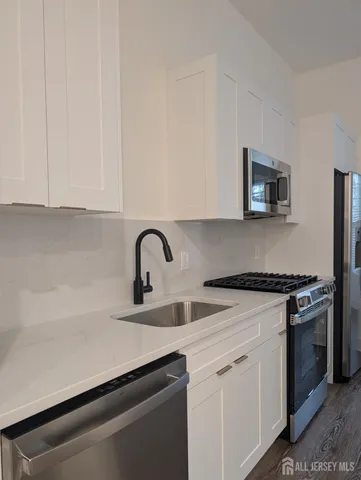 a kitchen with granite countertop white cabinets and stainless steel appliances