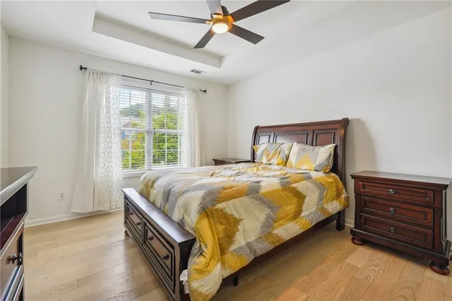 a spacious bedroom with a bed a dresser and a large window
