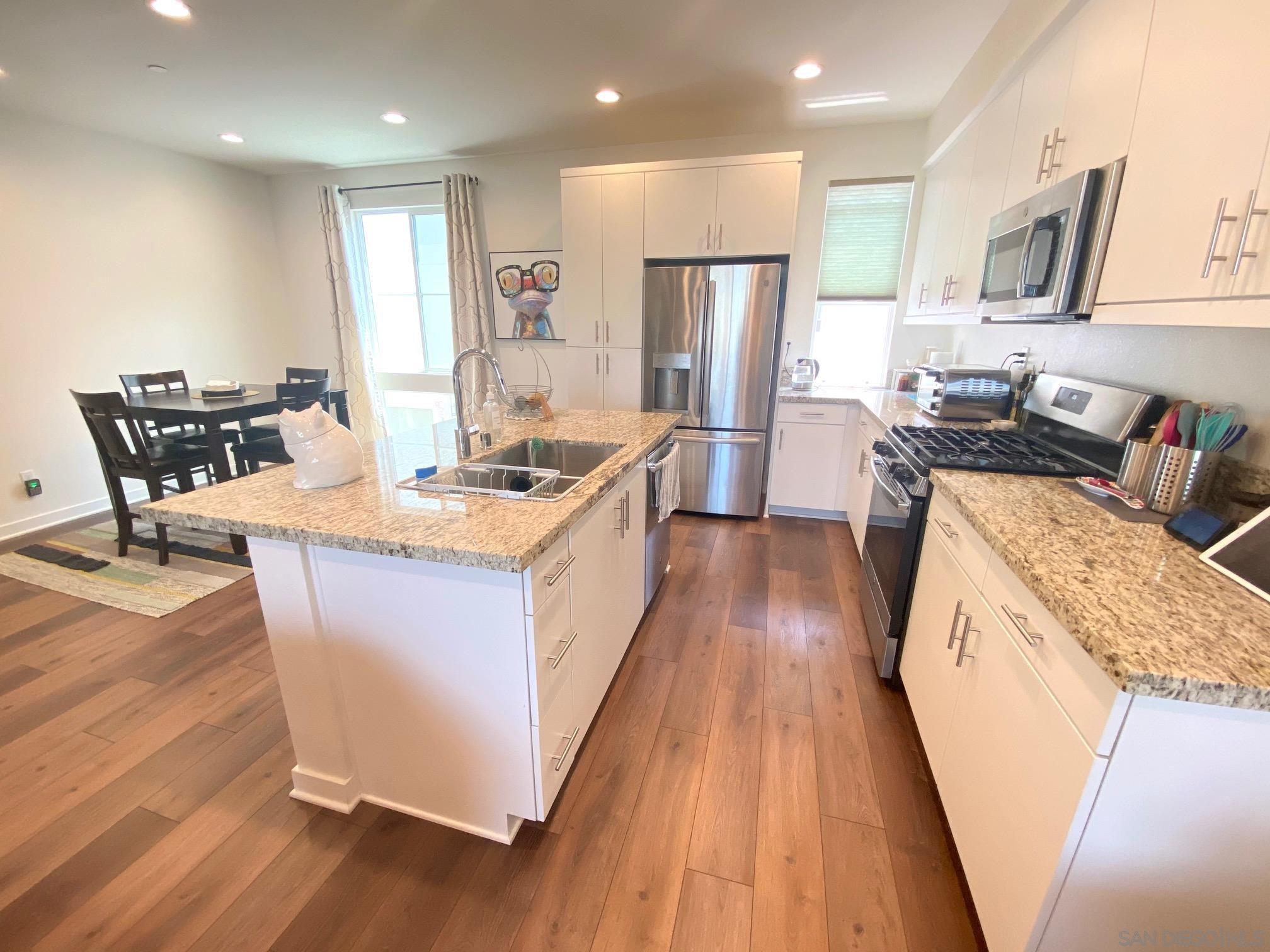 2135 Celestial Way, Unit 2 Chula Vista, CA 91915 - Photo 3 of 24 a kitchen with stainless steel appliances granite countertop a sink a stove a refrigerator and island with wooden floor