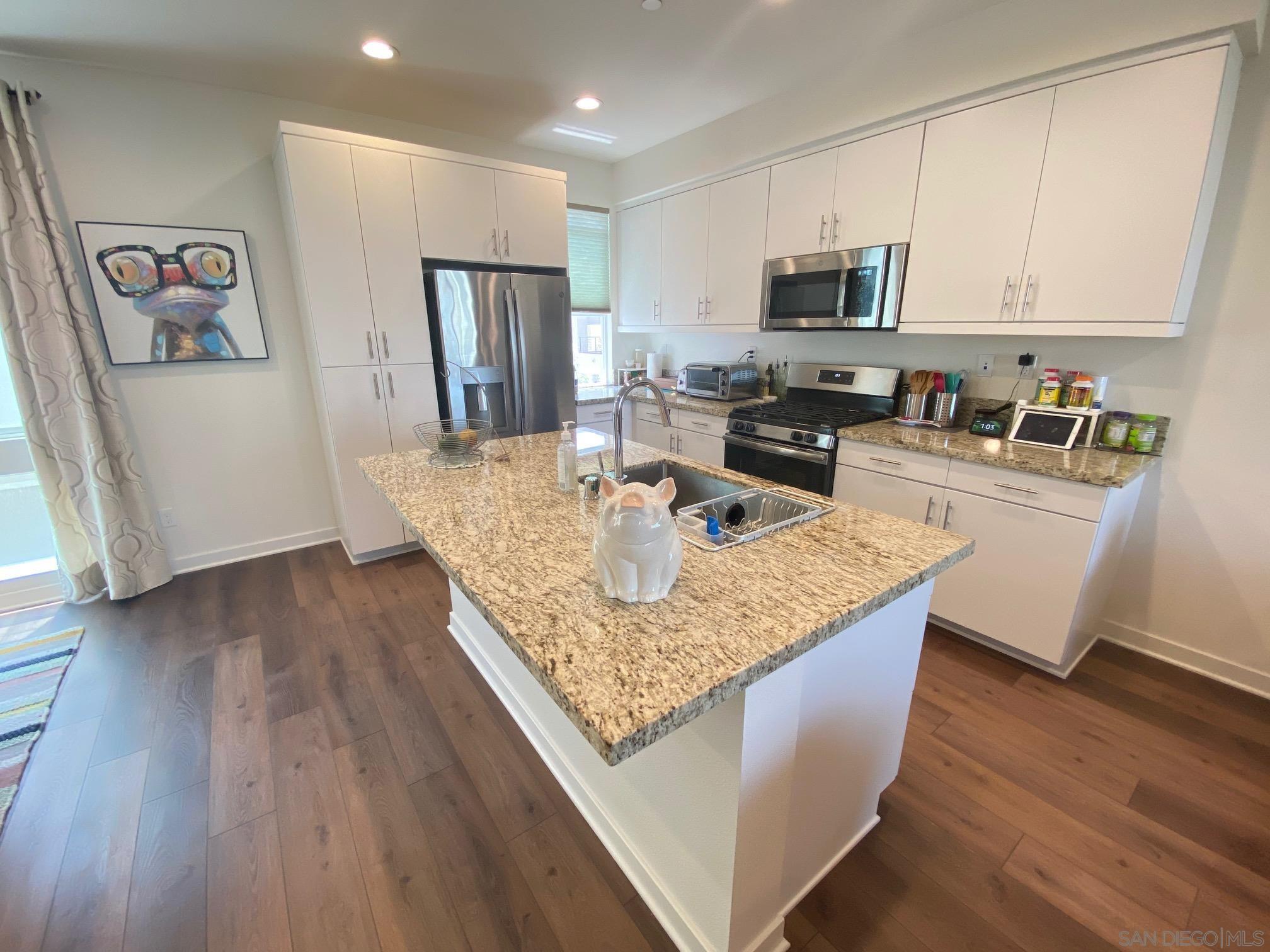 2135 Celestial Way, Unit 2 Chula Vista, CA 91915 - Photo 4 of 24 a kitchen with granite countertop a refrigerator a stove a sink a microwave and wooden floor