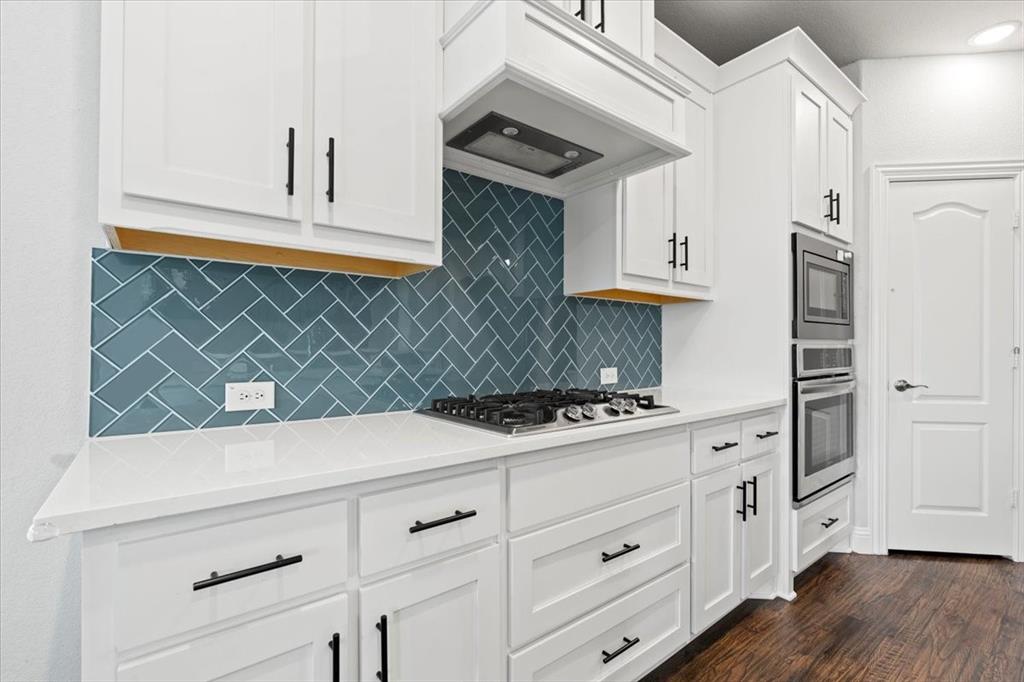 620 Shadow Trail Frisco, TX 75033 - Photo 4 of 36 Kitchen featuring white cabinetry with black hardware, white countertops, herringbone tile backsplash, a built-in gas cooktop, and stainless steel double ovens