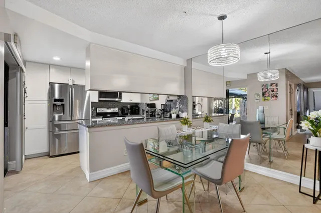 a kitchen with stainless steel appliances kitchen island granite countertop a table and chairs in it