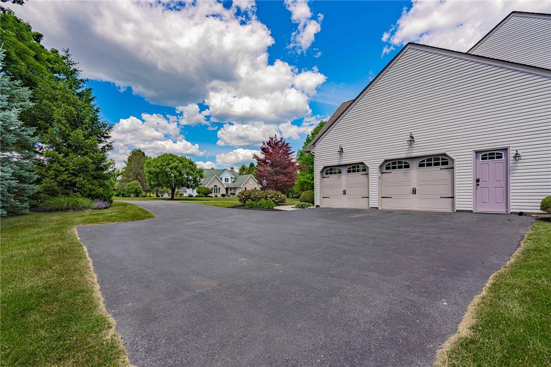 6000 Pond View Terrace Bath, PA 18014 - Photo 6 of 69 A spacious asphalt driveway leads to a classic beige-sided garage with multiple bay doors and inviting curb appeal.