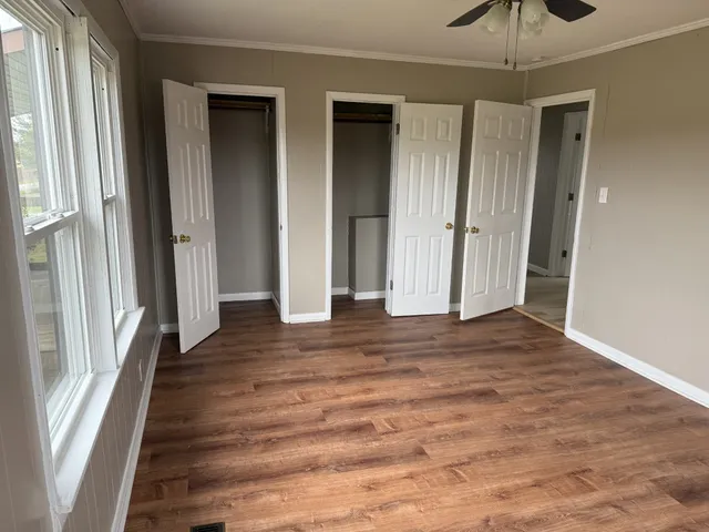 a view of a hallway with wooden floor and a ceiling fan