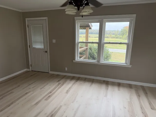an empty room with wooden floor and windows