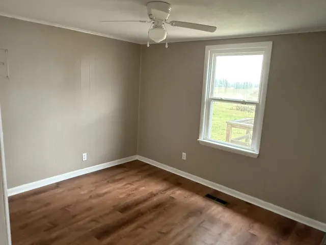 an empty room with a window and ceiling fan