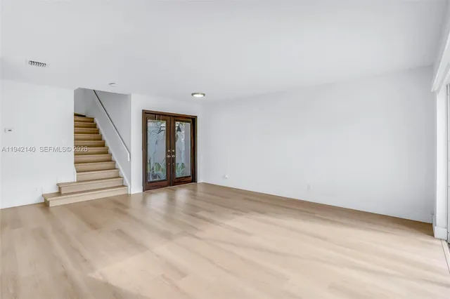 a view of an empty room with window and wooden floor