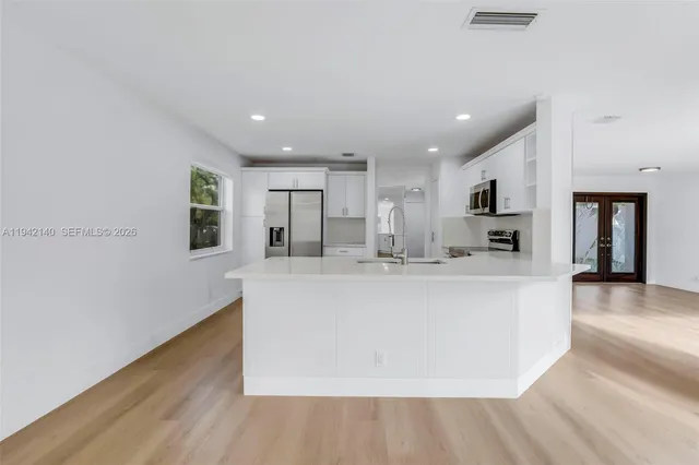 a view of kitchen with kitchen island a sink wooden floor and a living room view