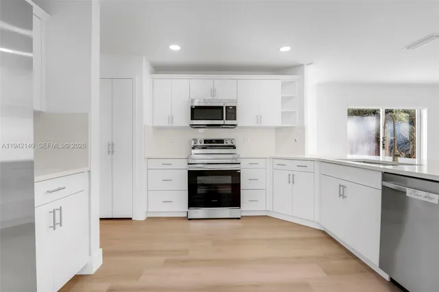 a kitchen with white cabinets and appliances