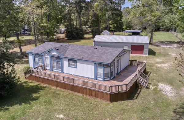 an aerial view of a house with swimming pool and large trees
