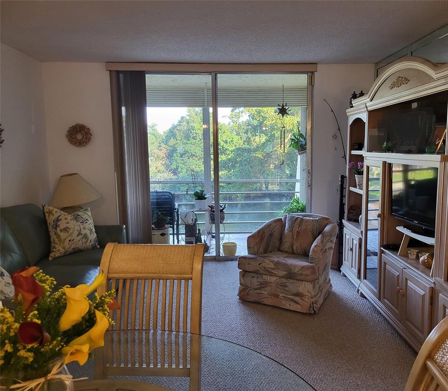 9070 Lime Bay Boulevard, Unit 309 Tamarac, FL 33321 - Photo 4 of 16 a living room with furniture and a flat screen tv