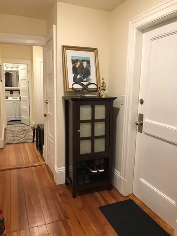 a view of a hallway with wooden floor and a bathroom