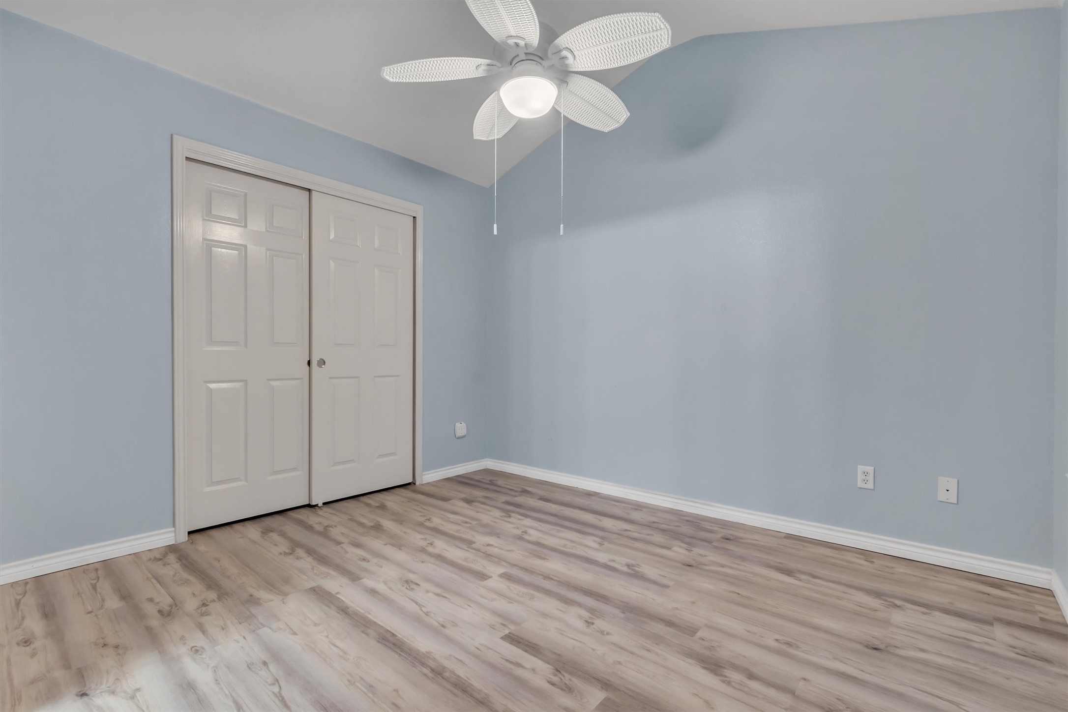 627 Scheel Road Kyle, TX 78640 - Photo 16 of 37 An airy bedroom showcases durable wood flooring and a practical bi-fold closet, perfect for comfortable living.
