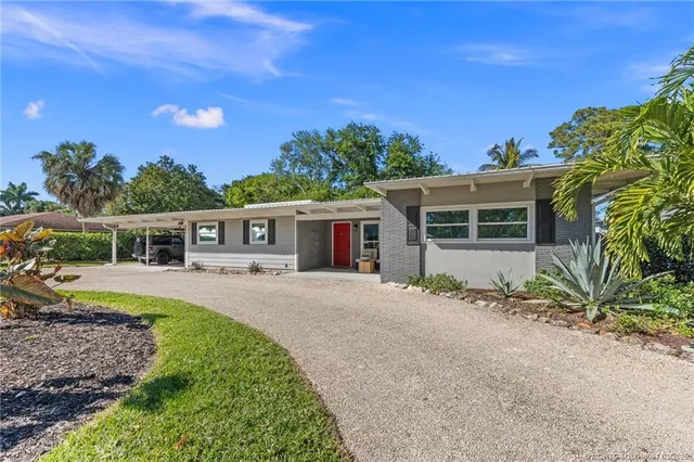 a front view of a house with a yard and potted plants