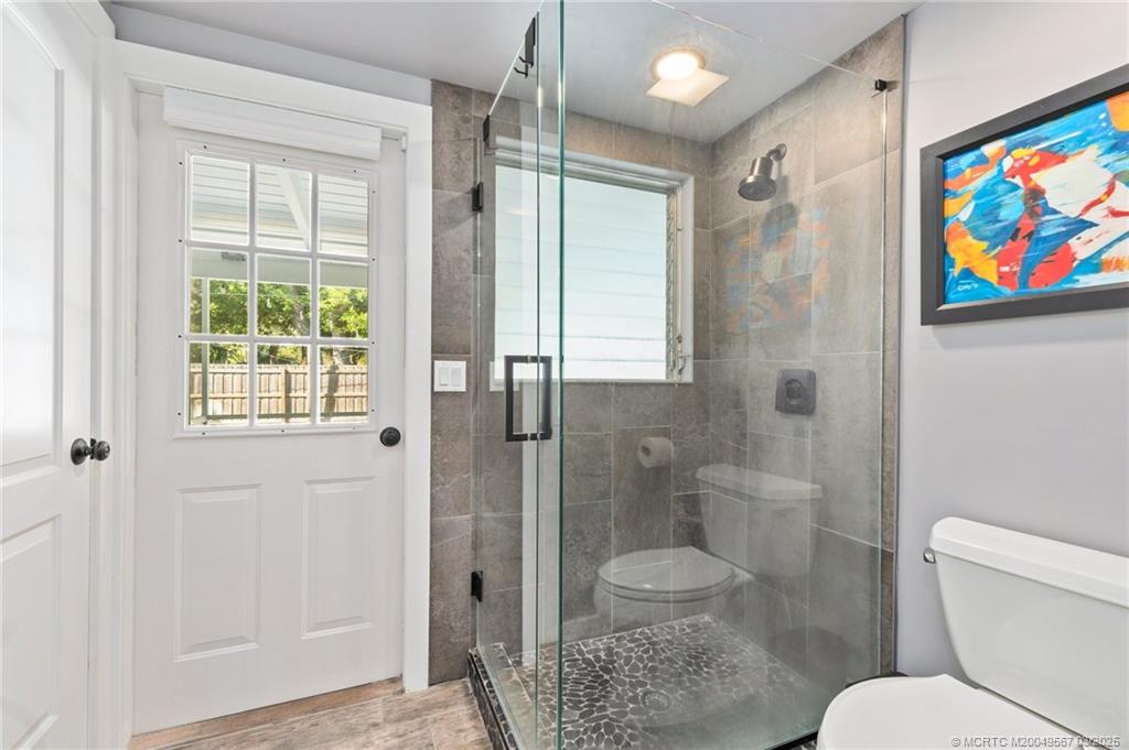 530 South Manor Drive Stuart, FL 34994 - Photo 32 of 55 a bathroom with a toilet a sink and glass door