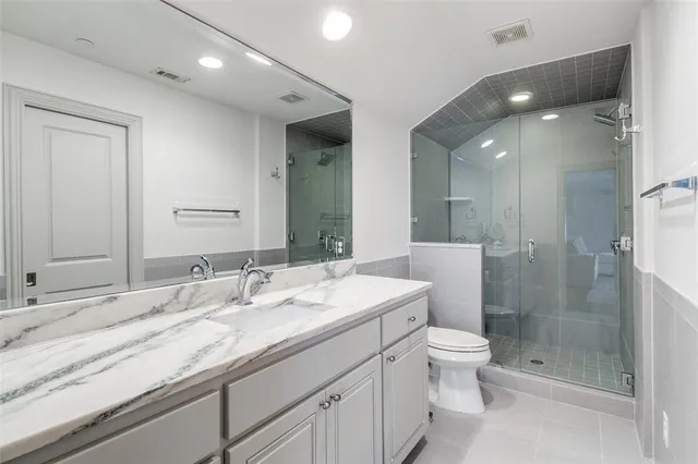a bathroom with a granite countertop sink a toilet a mirror and shower