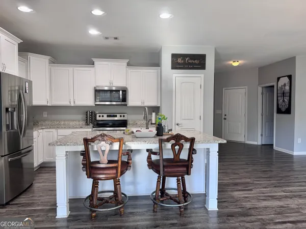 a kitchen with stainless steel appliances kitchen island granite countertop a refrigerator and a stove top oven