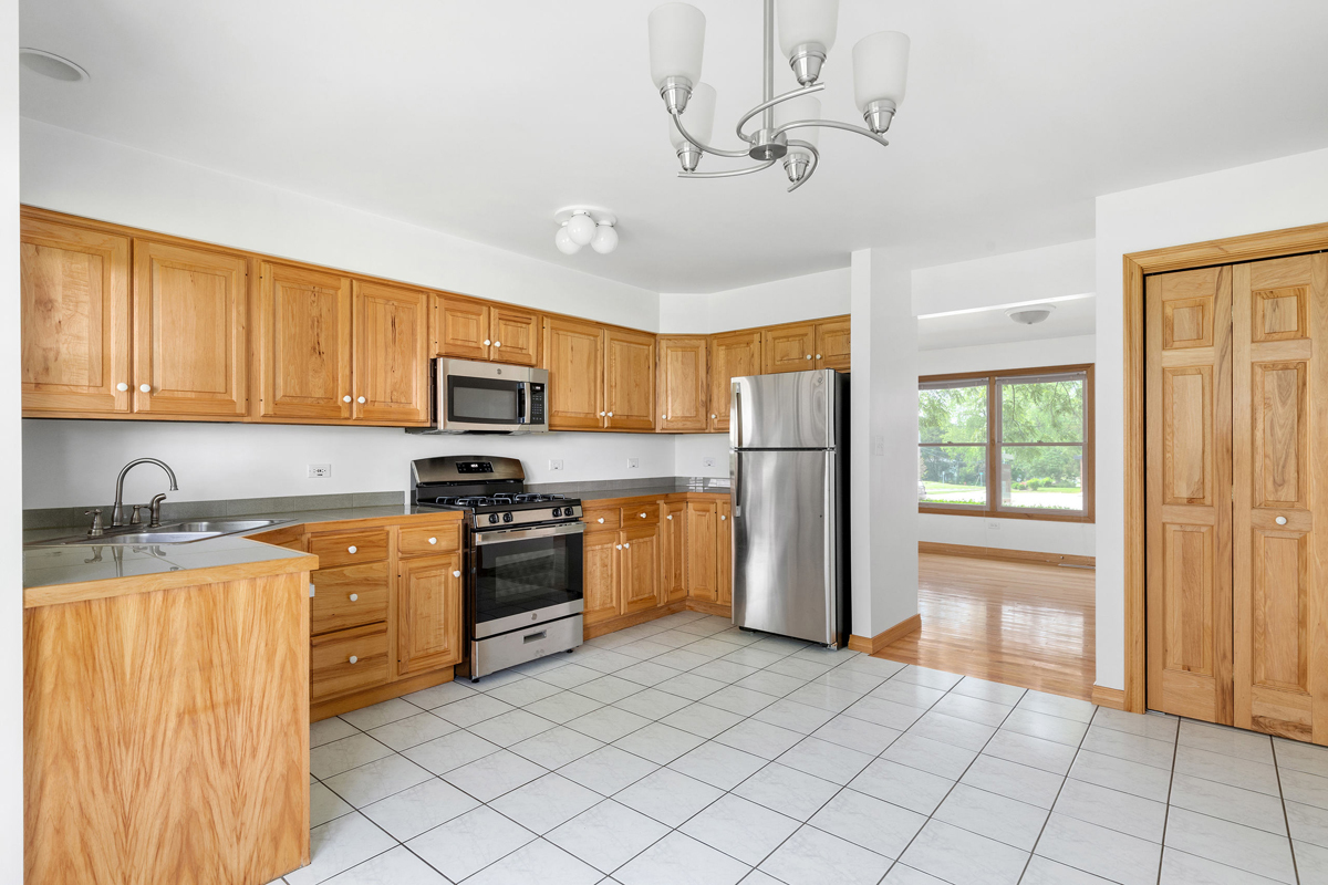 426 East 5th Street Lockport, IL 60441 - Photo 7 of 20 a kitchen with stainless steel appliances granite countertop a refrigerator a stove top oven a sink dishwasher and a refrigerator with wooden cabinets