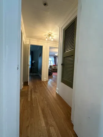 a view of a hallway with wooden floor and furniture