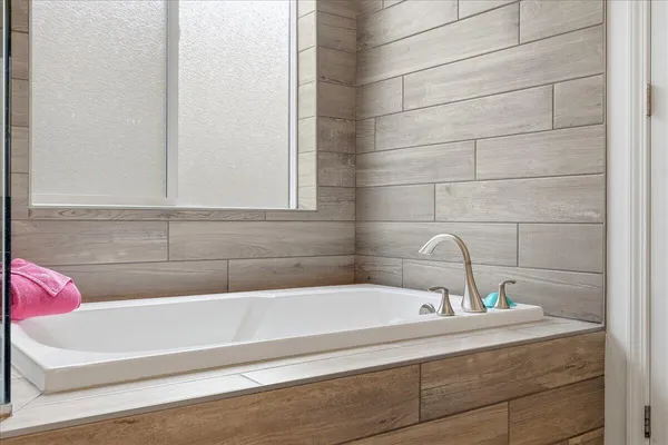 a bathroom with a tub shower and window