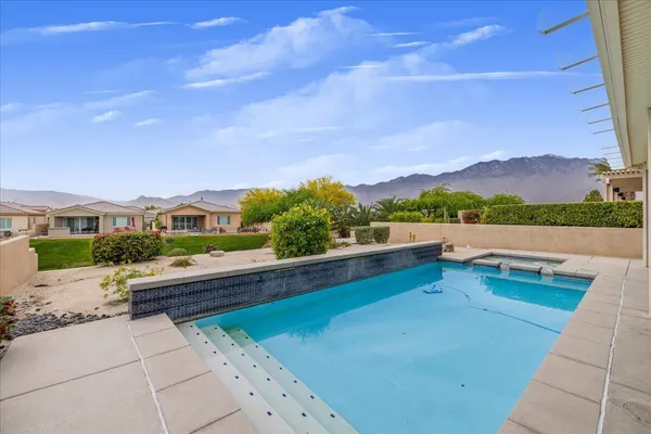 a view of swimming pool with seating space and mountain view in back