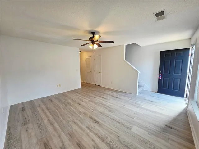 a view of a room with wooden floor and a ceiling fan