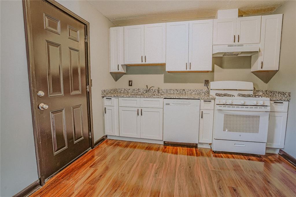 2877 Whispering Hills Drive, Unit 2875 Atlanta, GA 30341 - Photo 4 of 18 a kitchen with granite countertop wooden floors and white stainless steel appliances