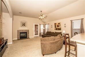 1409 Rosson Road Little Elm, TX 75068 - Photo 21 of 34 Spacious living area featuring a tile-surround fireplace, vaulted ceiling, and ceiling fan