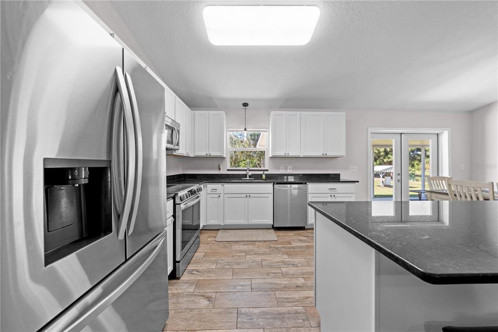 3198 Cherokee Road St. Cloud, FL 34772 - Photo 14 of 43 a kitchen with stainless steel appliances granite countertop a sink refrigerator and cabinets