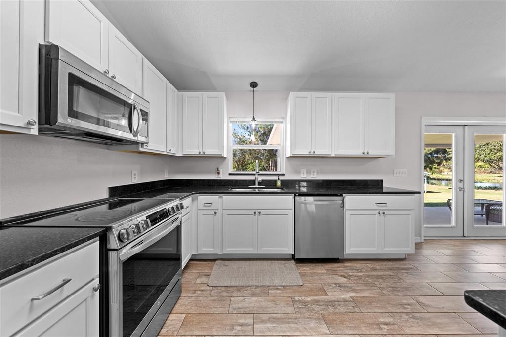3198 Cherokee Road St. Cloud, FL 34772 - Photo 15 of 43 a kitchen with stainless steel appliances granite countertop a stove top oven microwave and cabinets