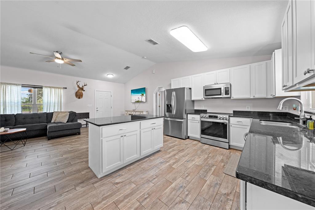 3198 Cherokee Road St. Cloud, FL 34772 - Photo 18 of 43 a large kitchen with cabinets wooden floor and stainless steel appliances