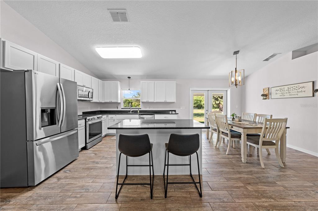 3198 Cherokee Road St. Cloud, FL 34772 - Photo 19 of 43 a kitchen with stainless steel appliances granite countertop a dining table chairs stove refrigerator and cabinets