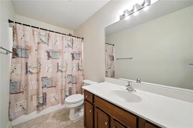 a bathroom with a granite countertop sink toilet a mirror and shower curtain