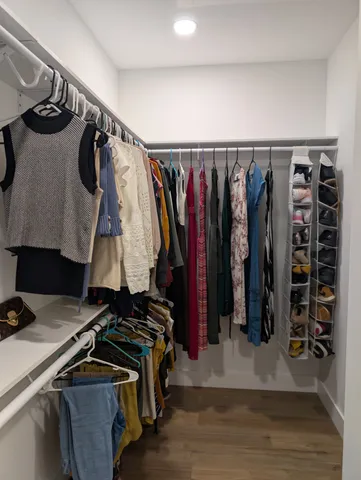 a view of walk in closet with clothes and shoes