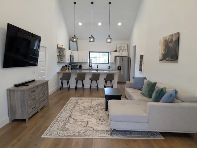 a living room with furniture a flat screen tv and kitchen view