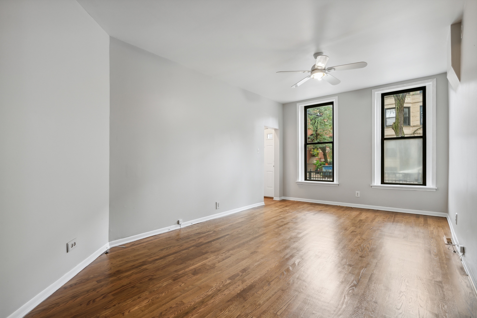 1439 West Lexington Street Chicago, IL 60607 - Photo 3 of 22 an empty room with wooden floor chandelier fan and windows