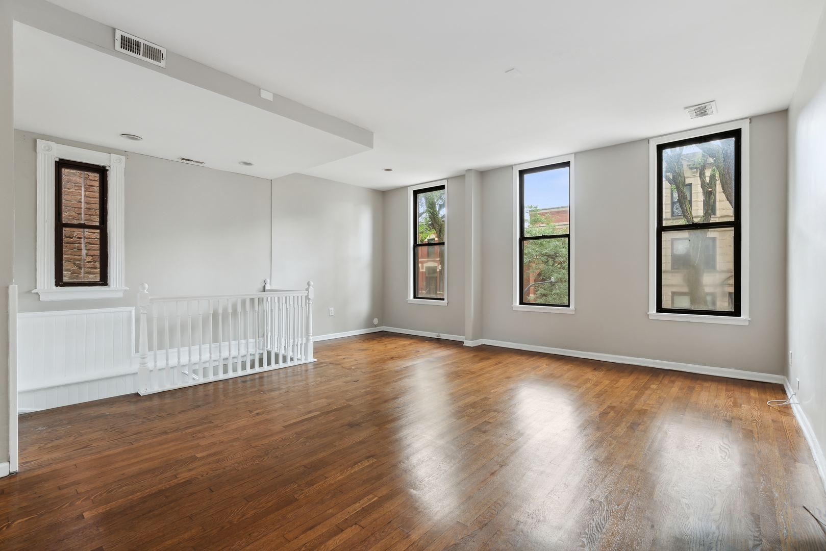 1439 West Lexington Street Chicago, IL 60607 - Photo 8 of 22 a view of an empty room with wooden floor and windows