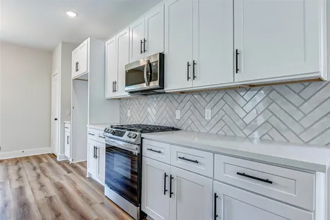 a kitchen with white cabinets and appliances