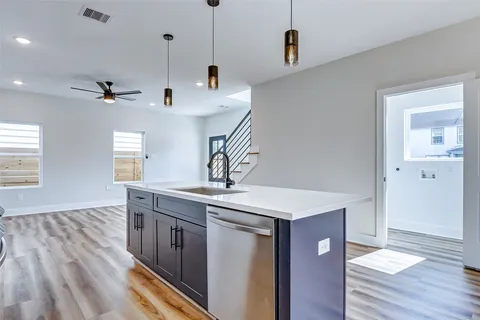 a kitchen with stainless steel appliances granite countertop a sink a stove and a wooden floor