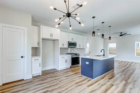 a large kitchen with stainless steel appliances kitchen island granite countertop a refrigerator and a stove top oven