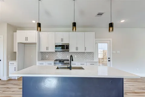 a kitchen with stainless steel appliances a sink a stove and white cabinets