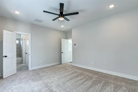 an empty room with a ceiling fan and carpet