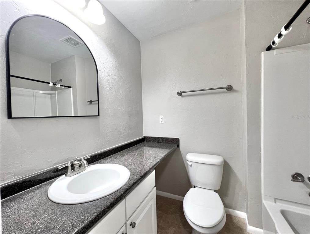 507 Northwest 39th Road, Unit 312 Gainesville, FL 32607 - Photo 22 of 34 a bathroom with a granite countertop toilet sink and mirror