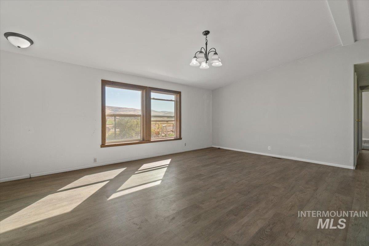 2284 Weiser River Road Weiser, ID 83672 - Photo 12 of 43 Spare room with dark wood-style flooring and a chandelier