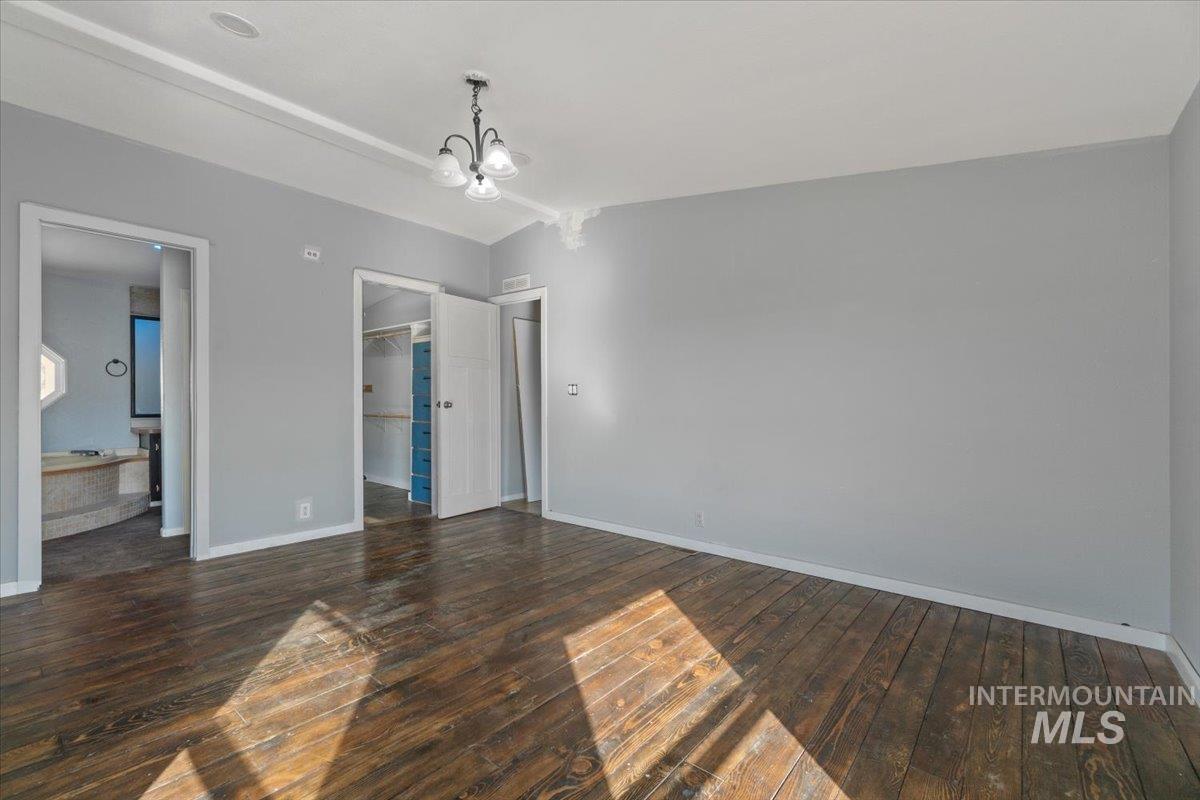 2284 Weiser River Road Weiser, ID 83672 - Photo 19 of 43 Unfurnished bedroom with a walk in closet, dark wood-style floors, lofted ceiling, and a chandelier