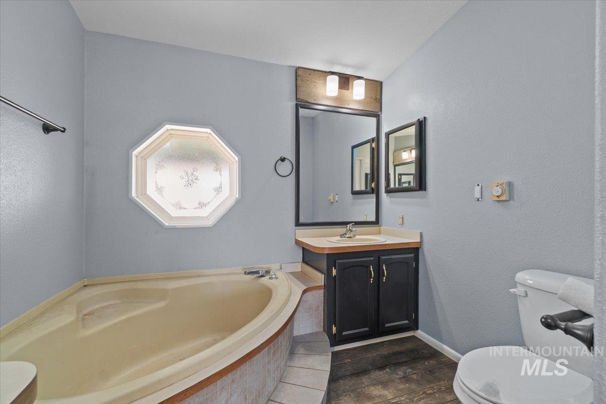 2284 Weiser River Road Weiser, ID 83672 - Photo 21 of 43 Bathroom featuring vanity, a garden tub, a textured wall, and dark wood finished floors